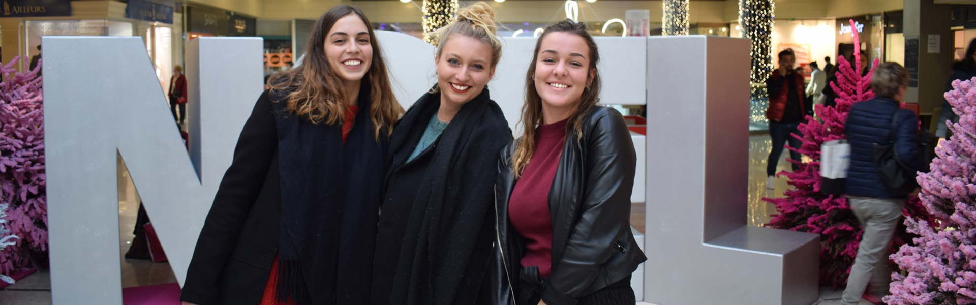 Trois femmes se font photographier par une borne photo devant un décor de noël dans un centre commercial